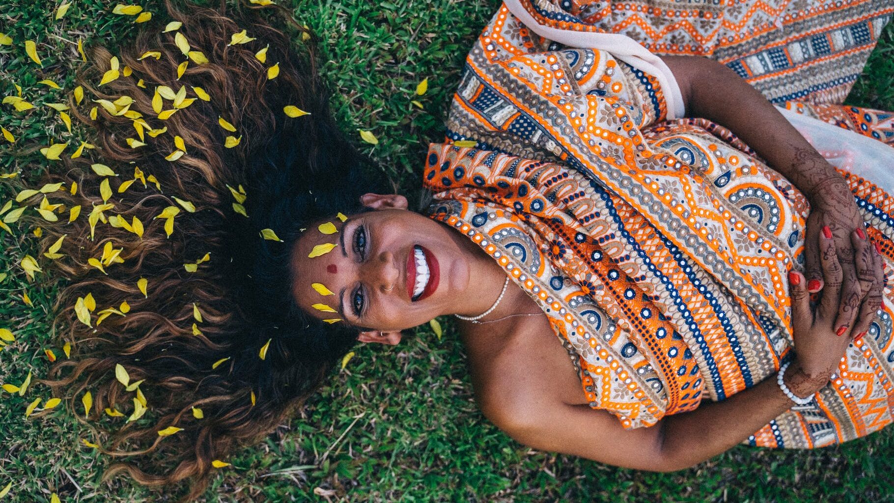 a smiling woman in sari lying on the ground