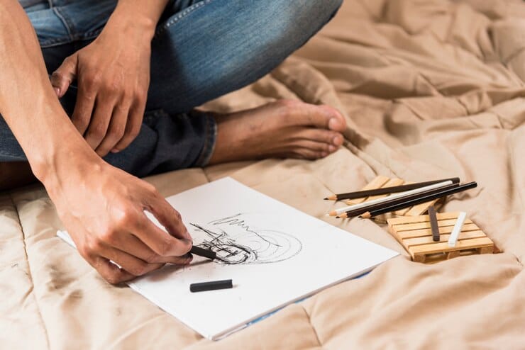 A person happily sketching in a notebook. Showing an example of drawing as a fun hobby when bored.