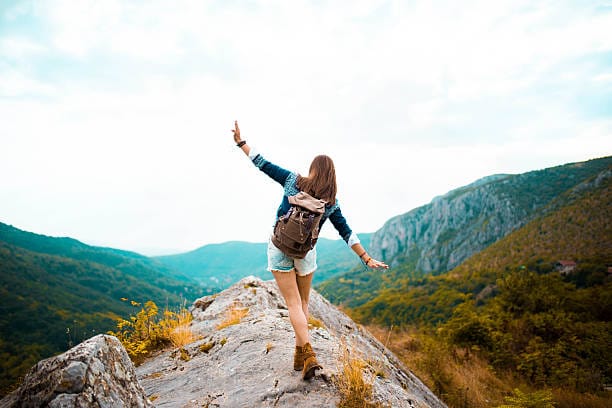 A person hiking on a mountain trail. An example of a hiking as a fun active hobby to do when bored.